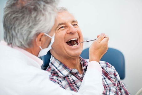 Older man having mouth examined by dentist