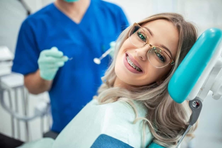 Young blonde woman with glasses getting teeth checked out