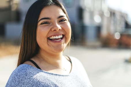 Young woman grey shirt smiling outside