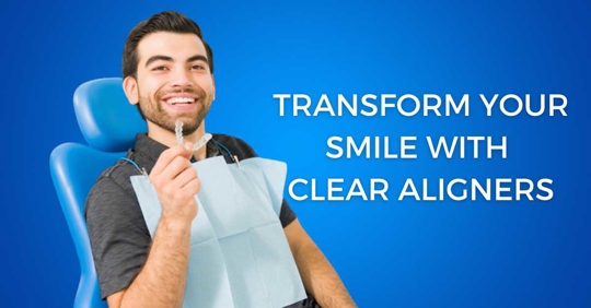 Man sitting in a dentist chair holding a clear aligner