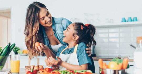 Woman and young girl cooking healthy food in kitchen