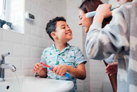Young boy brushing teeth with family