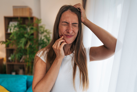 Stressed girl holds her jaw due to tooth pain