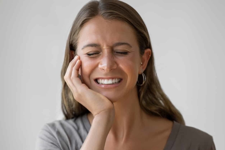 Woman holding her jaw and grimacing in pain