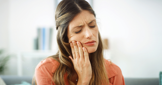 Woman holding cheek due to tooth pain