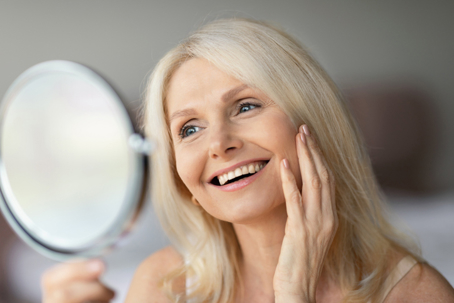 Woman looking in mirror admiring her smile